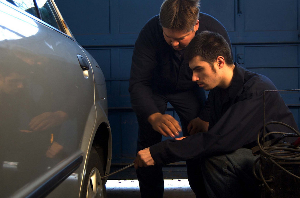 Two people working together to change a car tire